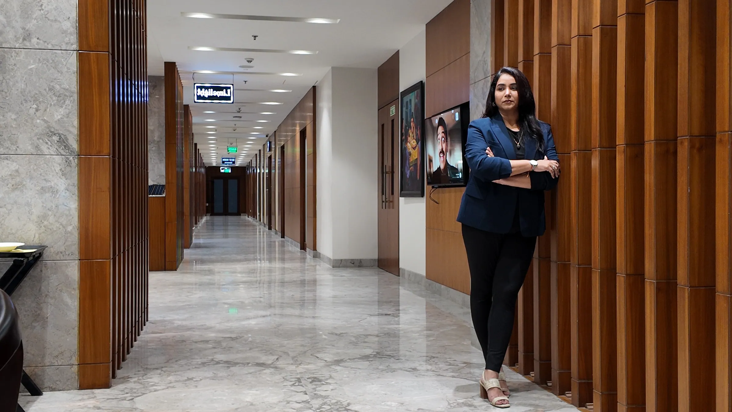 Sneha standing in a quiet wood-lined hallway