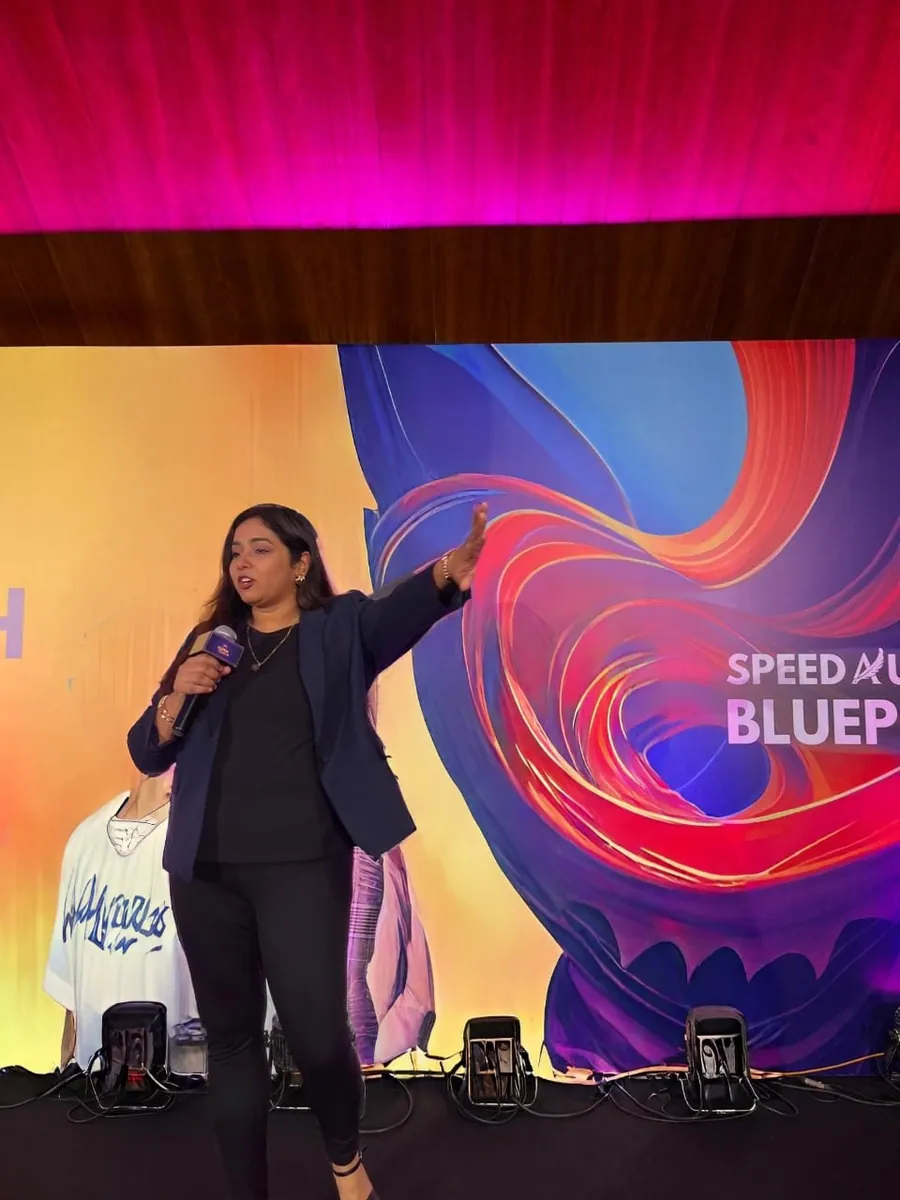Sneha speaking to an audience on stage